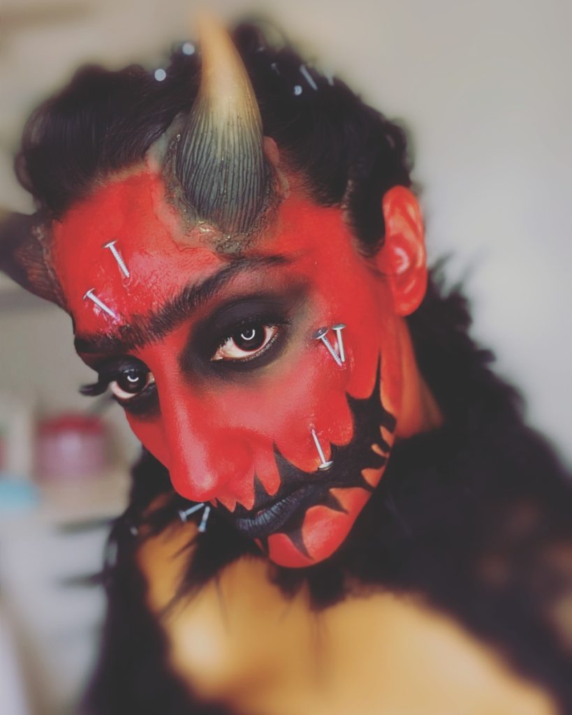 Frau mit rotem Teufel-Halloween-Make-up und Hörnern